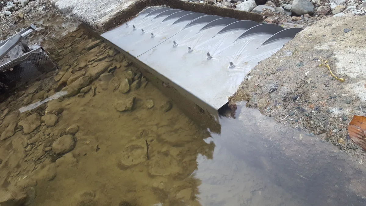 A Coanda intake screen partly buried in sediment after a flood