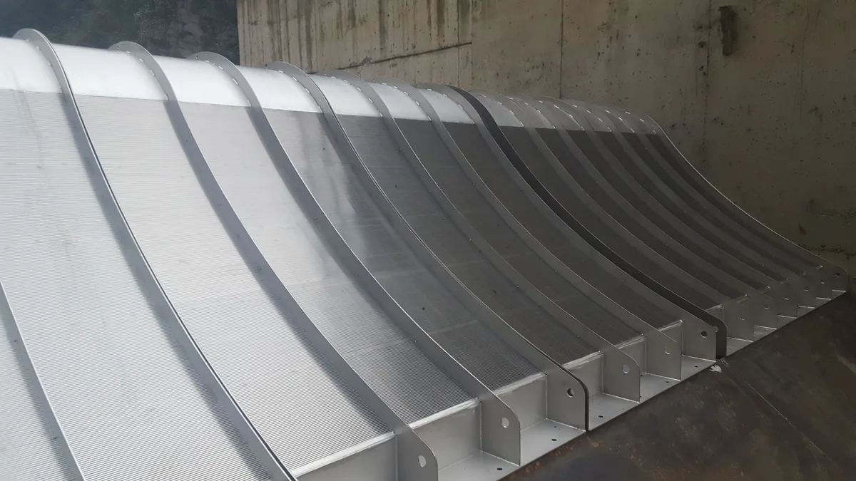 A large Coanda intake screen in a concrete structure, its curved profile seen along the full length