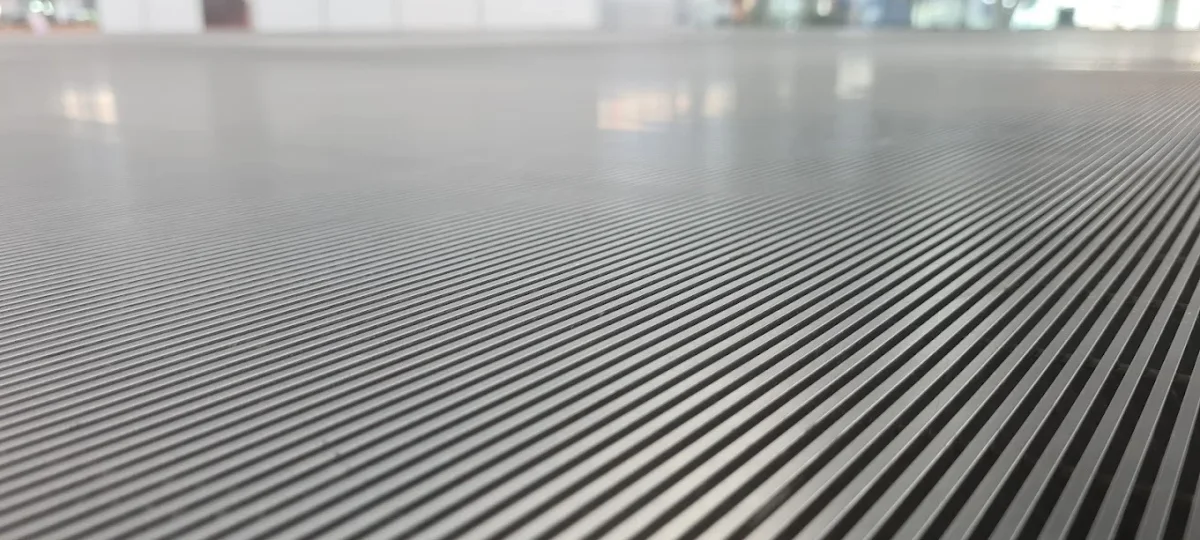 A wedge-wire surface photographed along its length, the triangular section of each wire visible at the near edge