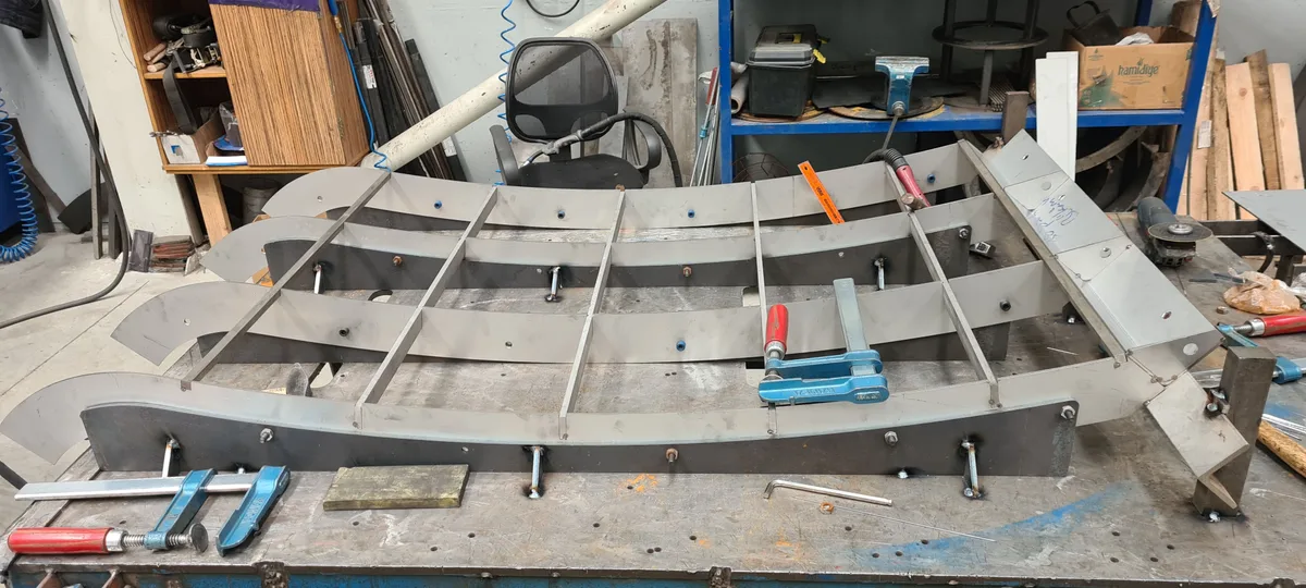 The curved support frame of a Coanda screen clamped on a workshop jig