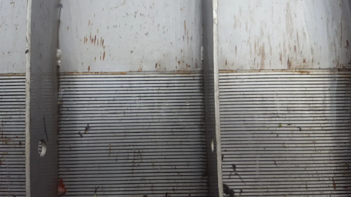 The wedge-wire face of a Coanda screen after a period in service, with mineral staining across the surface