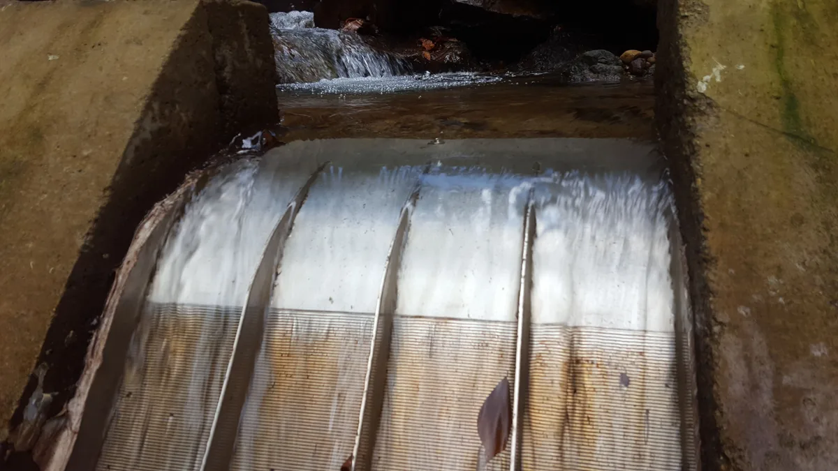 Close view of water crossing the wedge-wire slots on the curved face of a Coanda screen