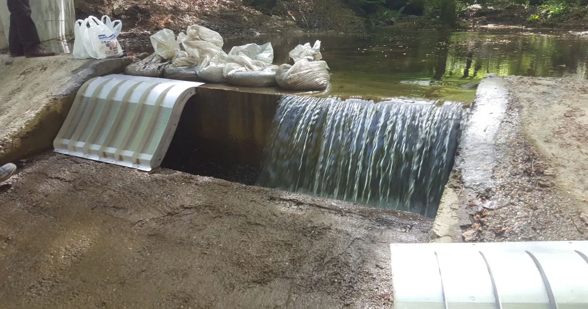 A small Coanda intake screen set into a concrete weir with water flowing over it