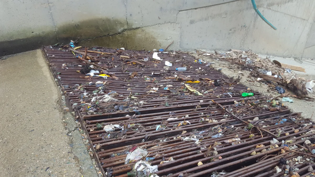 Bir nehir su alma yapısındaki geleneksel çelik çubuk ızgara (bar); yüzeyinin tamamı dallar, yapraklar ve plastik yüzen tortu ile tıkanmış durumda