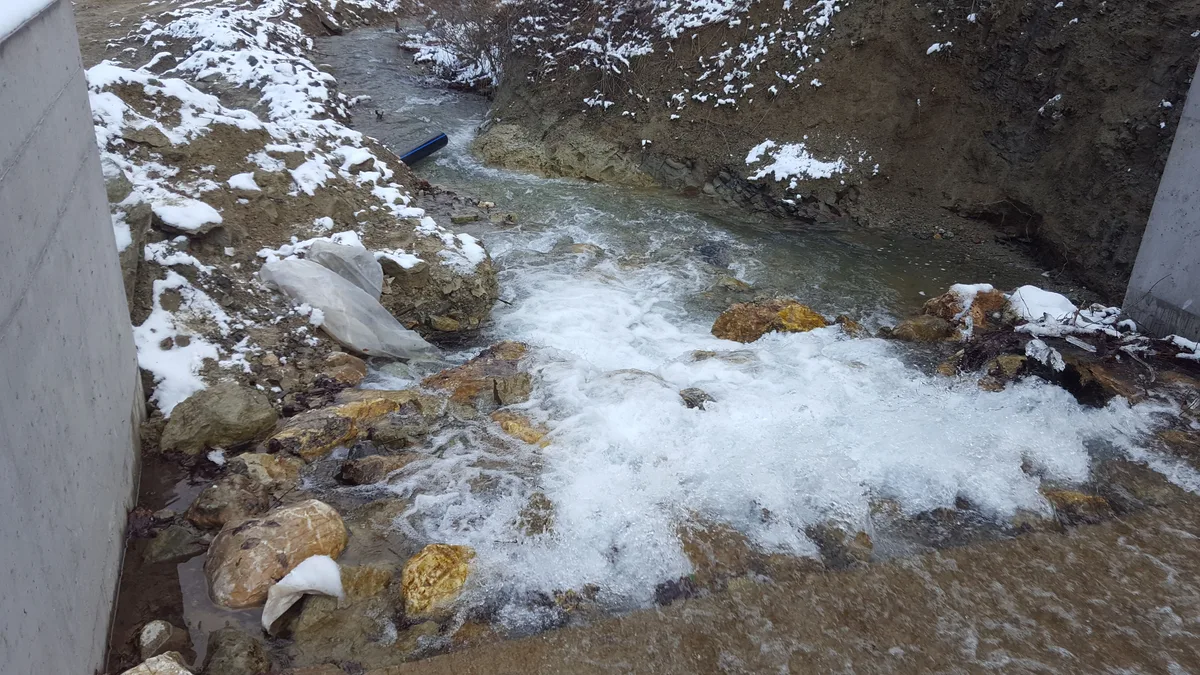 Kışın bir dağ deresi su alma yapısı; her iki kıyı boyunca kar ve buz