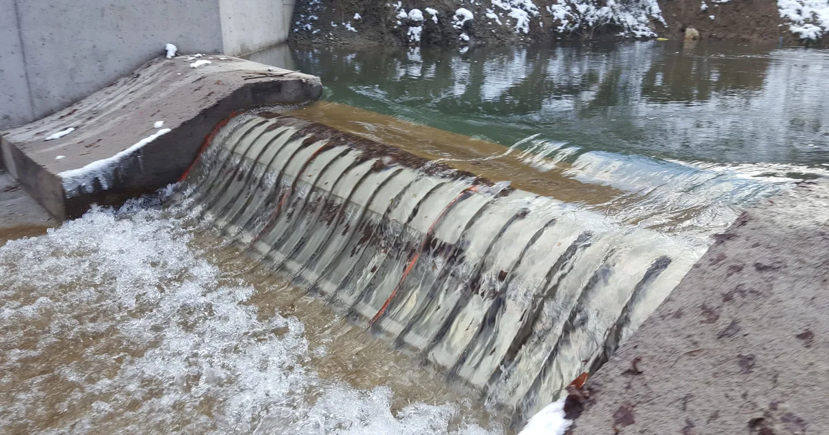A Coanda intake screen running in winter, snow banked along the structure and water flowing over the screen face