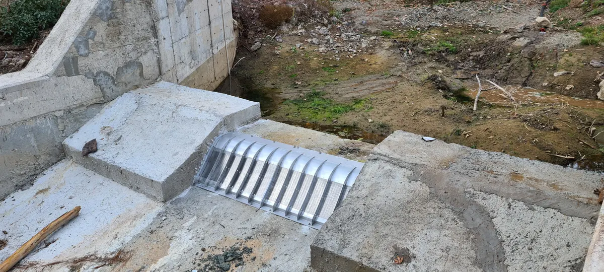A Coanda intake screen in a small concrete weir with the collection channel beside it