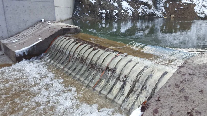 The Muratbey intake in January 2018, two months after commissioning: clear water pooled behind the weir and flowing in a thin sheet over three Coanda screens fitted with protection bars