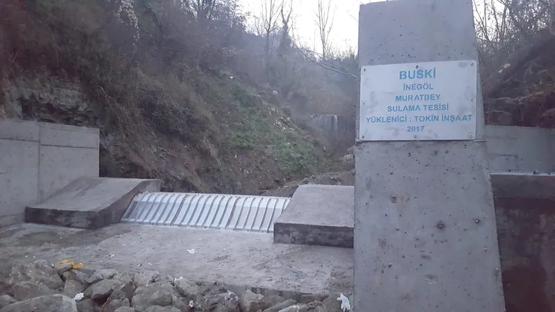 Rejillas de toma Coanda 3 x ADENCO-45-1, toma de 105 l/s para riego, obra de toma de BUSKI Muratbey con el cartel de la obra, Bursa, Türkiye