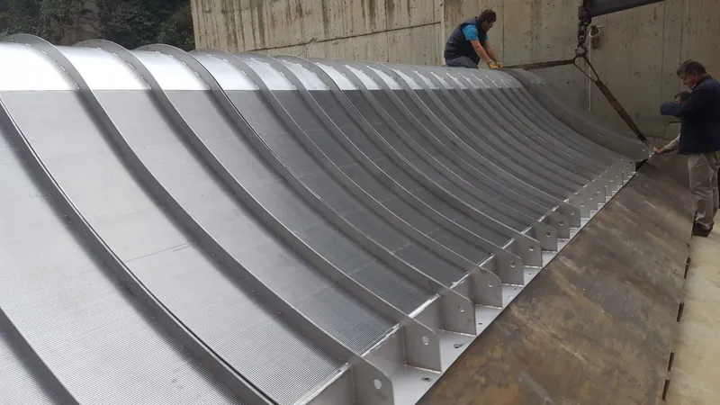 ADENCO engineers lowering a large Coanda intake screen into its concrete intake structure with lifting slings during installation