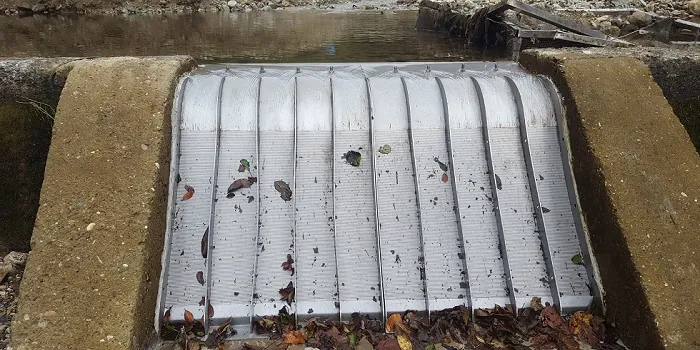 Rejillas de toma Coanda 2 x ADENCO-70-0.75, toma de 100 l/s para agua potable, rejilla Coanda ancha entre muros de hormigón con hojas de otoño sobre ella, vista desde arriba, Trabzon, Türkiye
